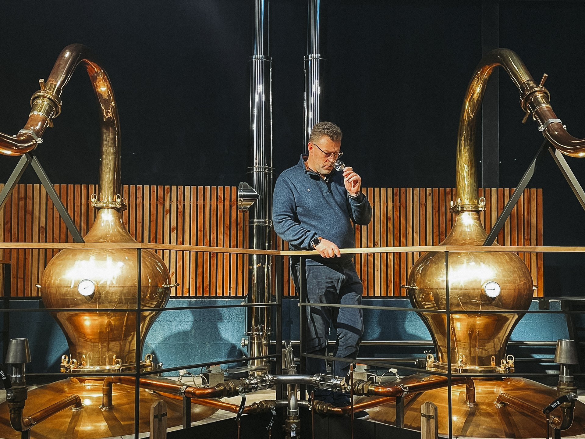 Régis Lemaitre expert whisky devant des alambics en cuivre
